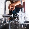 Running and splashing fresh water from kitchen faucet filling gl